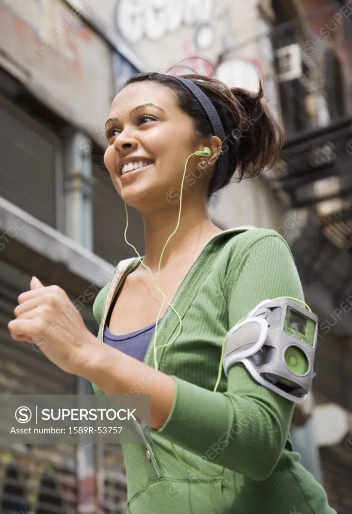 Mixed Race woman wearing headphones and jogging