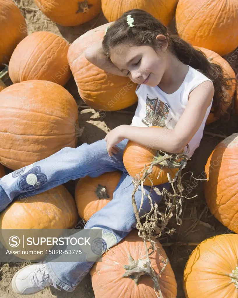 Hispanic girl laying in pumpkin patch