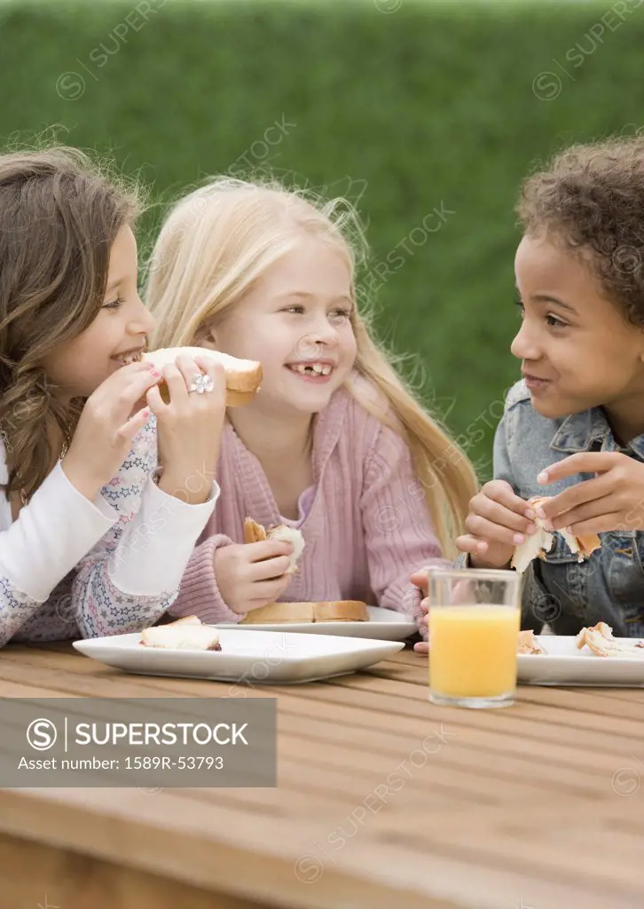 Multi-ethnic girls eating sandwiches
