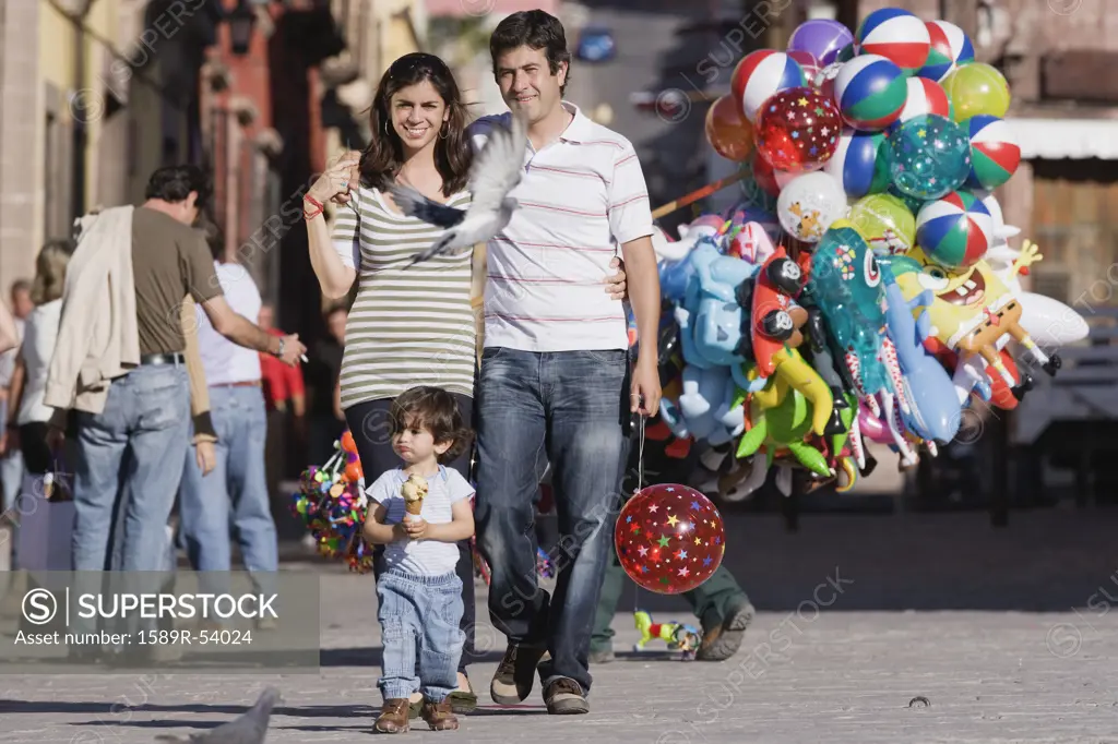 Hispanic family walking with balloon and ice cream
