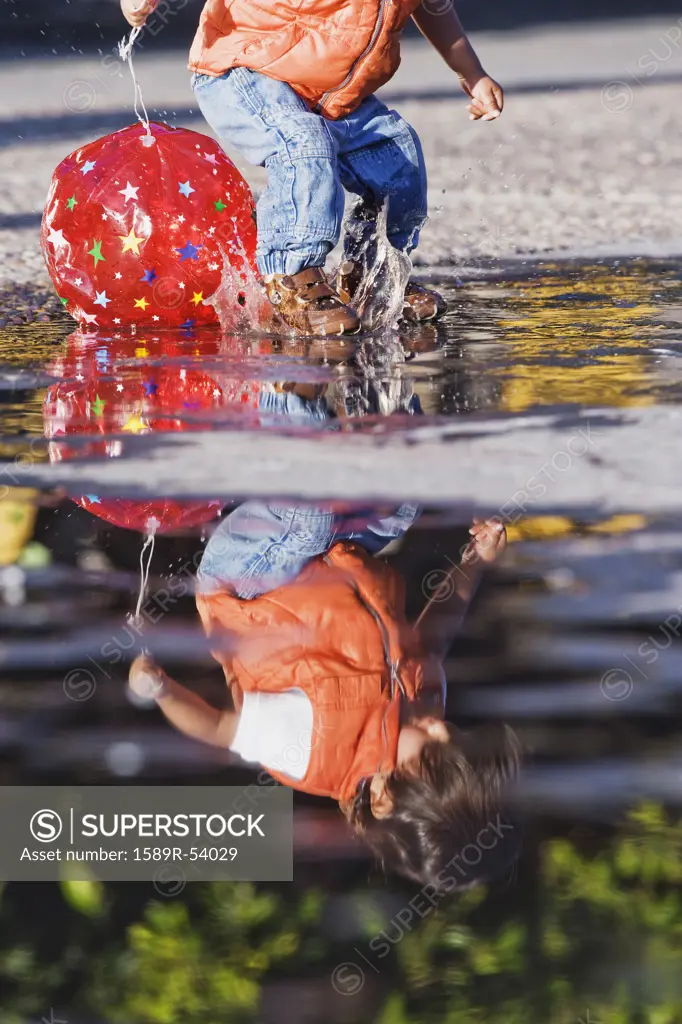 Hispanic boy splashing in puddle
