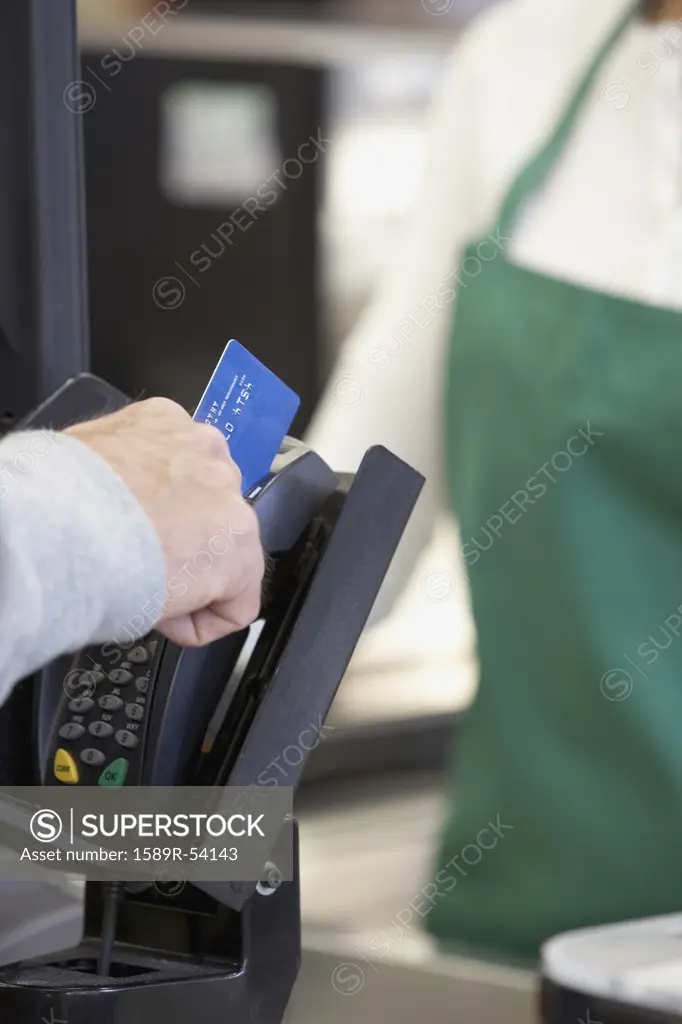 Man swiping credit card at grocery store checkout