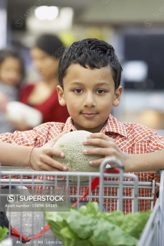 Indian boy holding fruit at grocery store