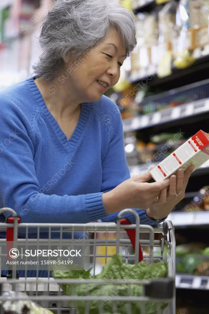 Senior Asian woman reading label at grocery store