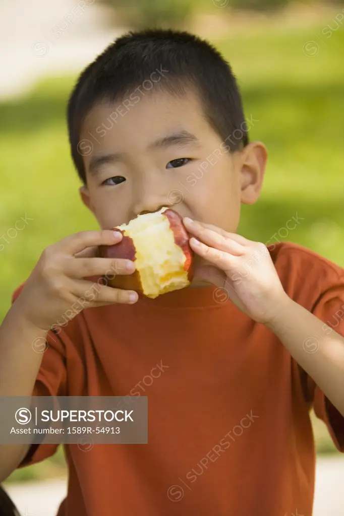 Asian boy eating apple