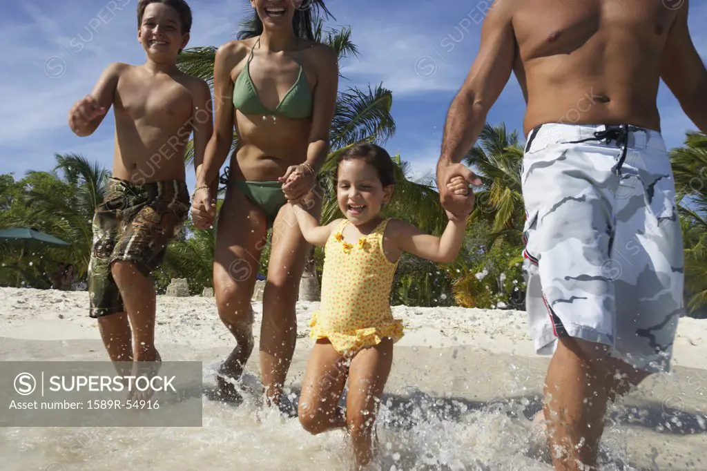 Hispanic family running into water