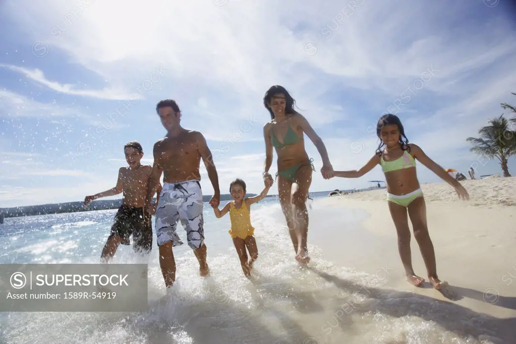 Hispanic family running in ocean surf