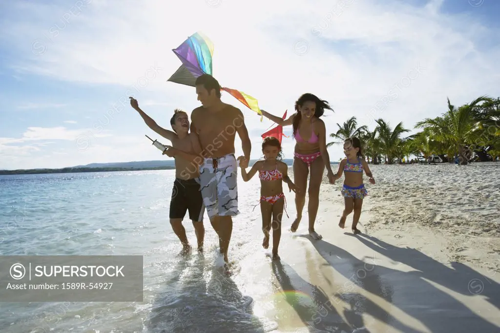 Hispanic family flying kite at beach
