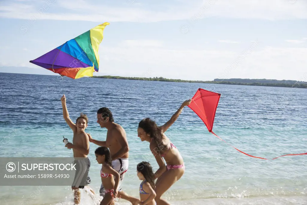 Hispanic family flying kites at beach