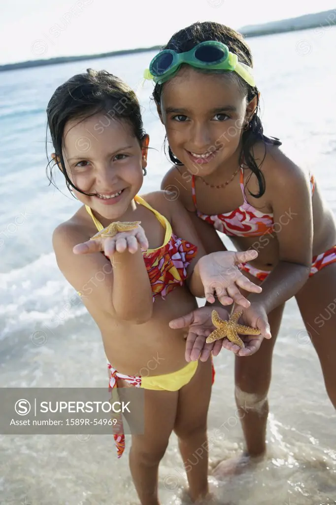 Hispanic sisters holding starfish