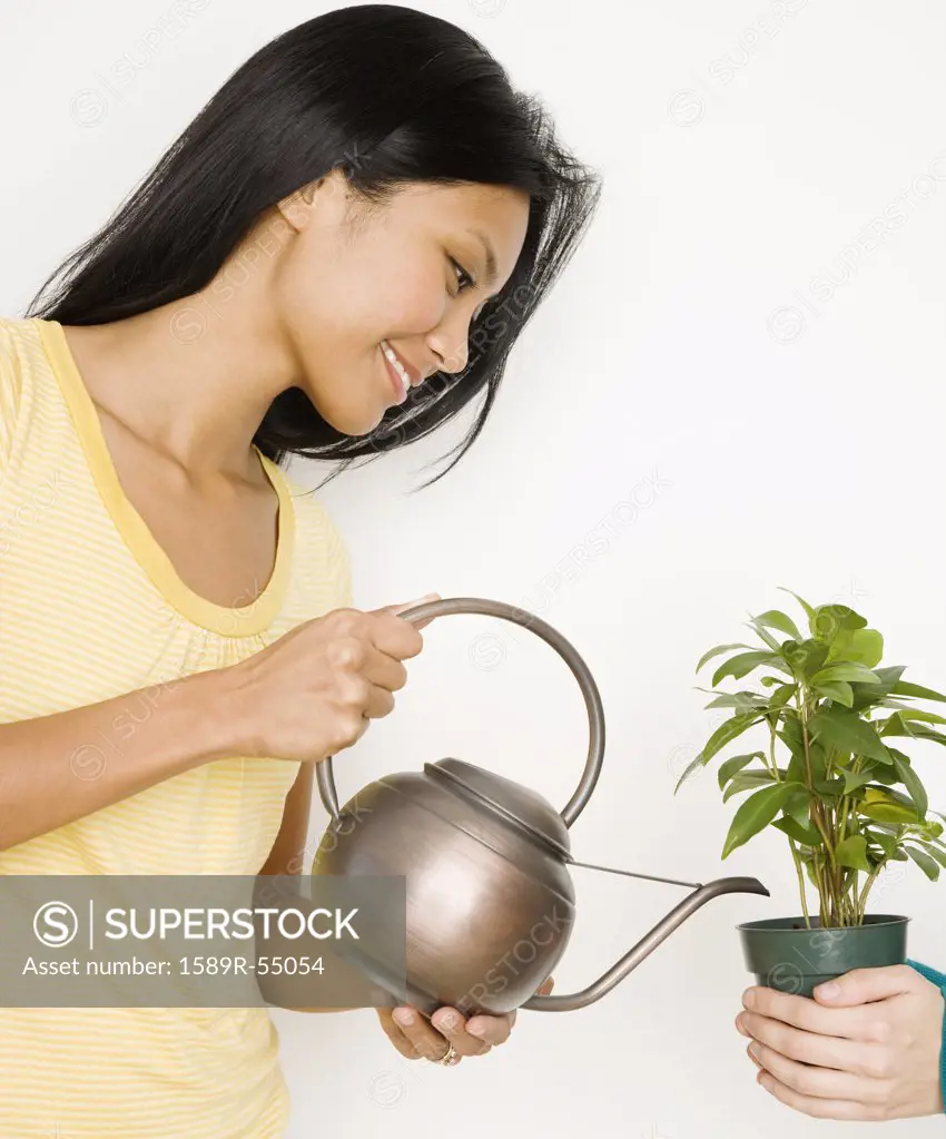 Pacific Islander woman watering potted plant
