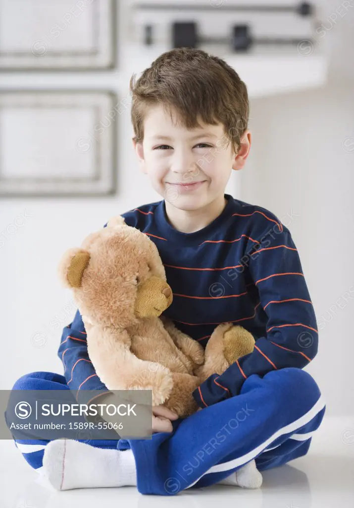 Hispanic boy with teddy bear in doctors office