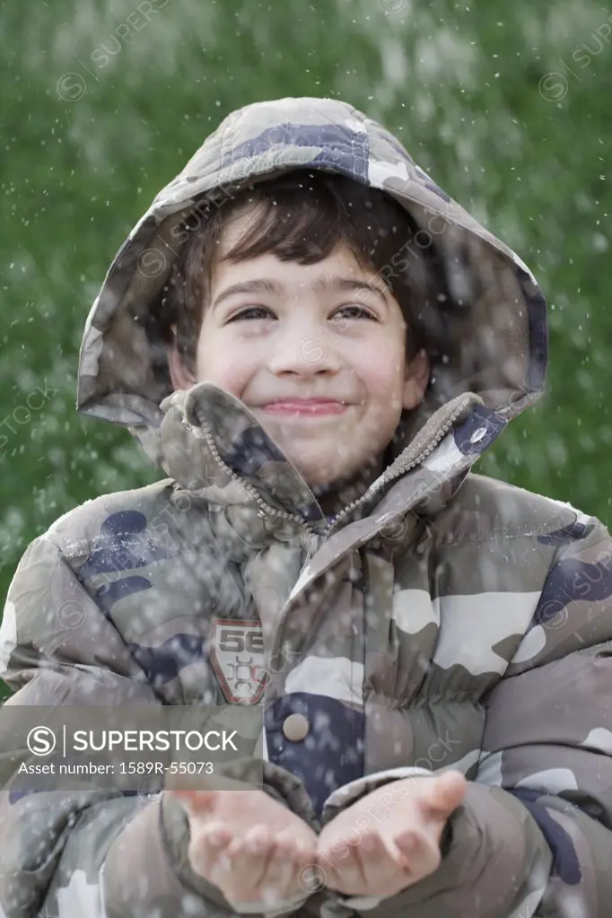 Hispanic boy with hands out in snow