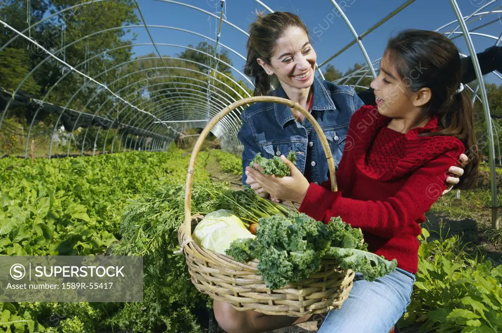 Multi-ethnic mother and daughter harvesting organic produce