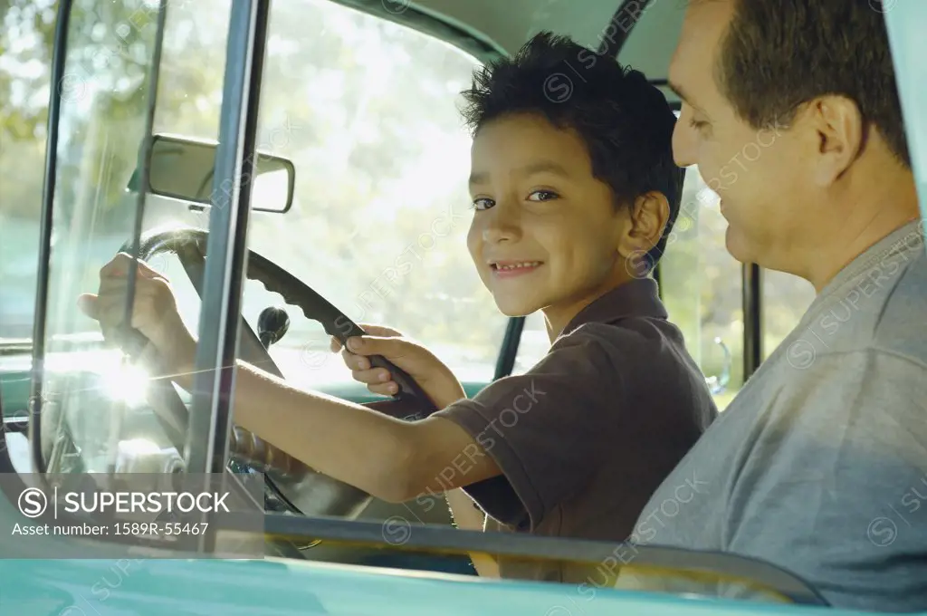 Hispanic father and son sitting in truck
