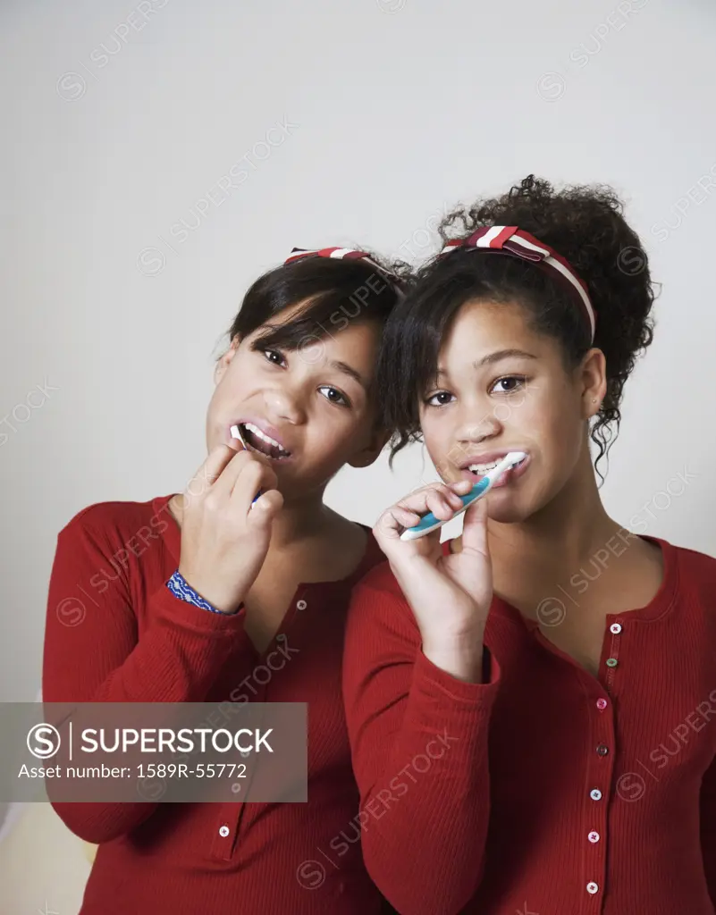 African twin sisters brushing teeth