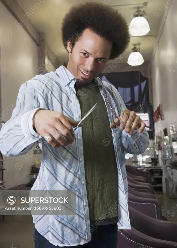 Mixed Race male hair stylist holding scissors