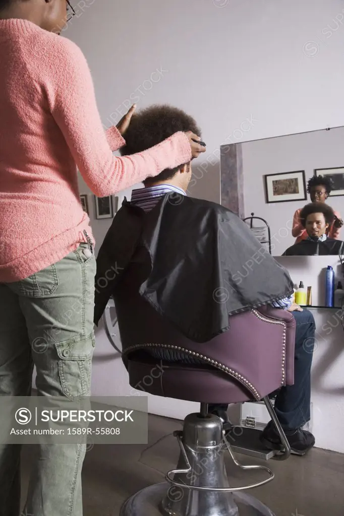 African hair stylist cutting Mixed Race mans hair