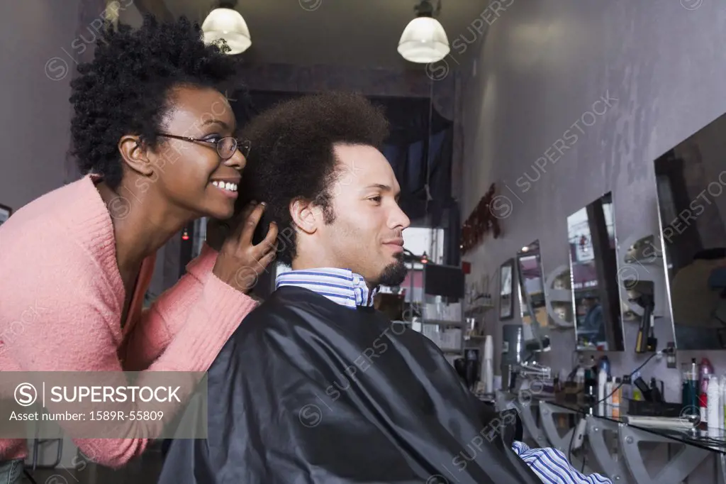 African hair stylist styling Mixed Race mans hair