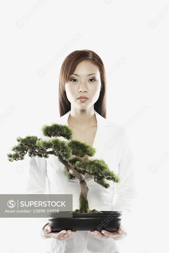 Asian businesswoman holding bonsai tree