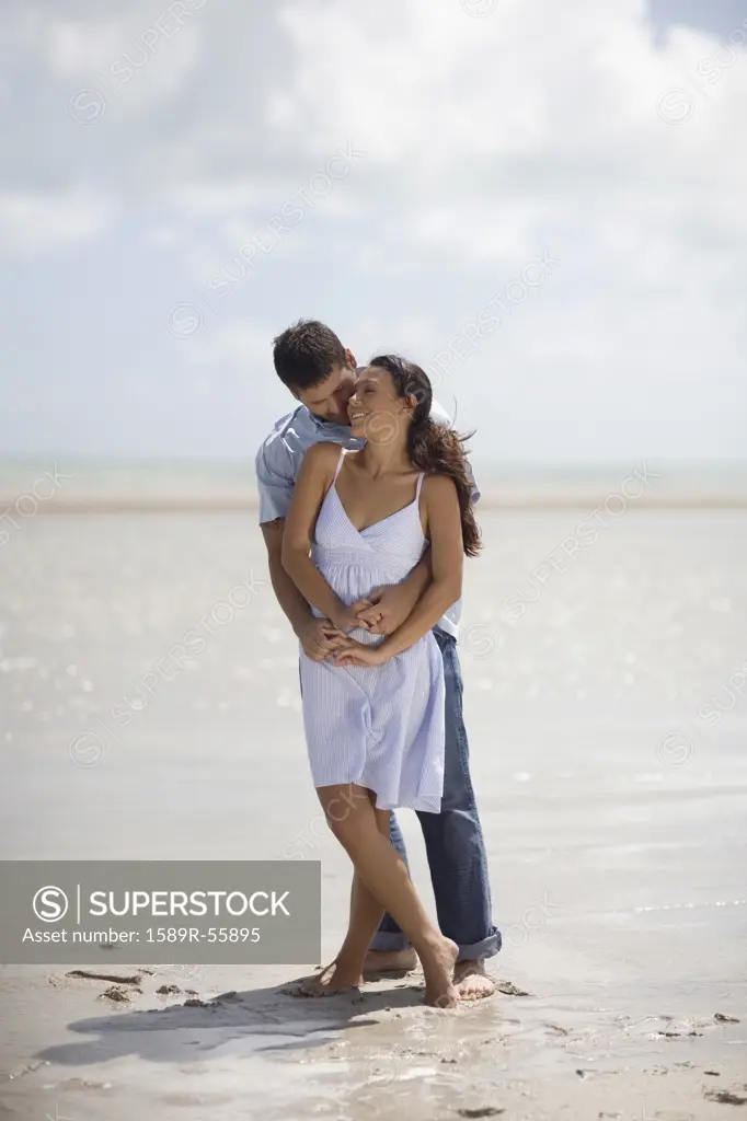 Hispanic couple hugging at beach