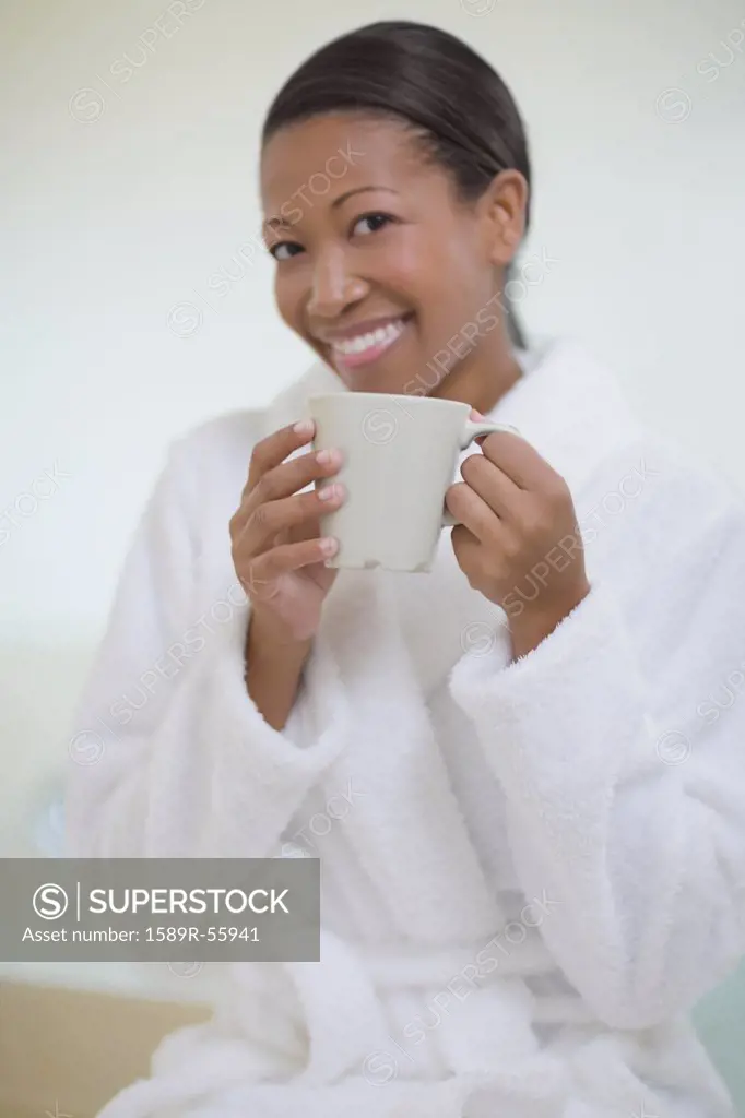 African woman in bathrobe drinking coffee