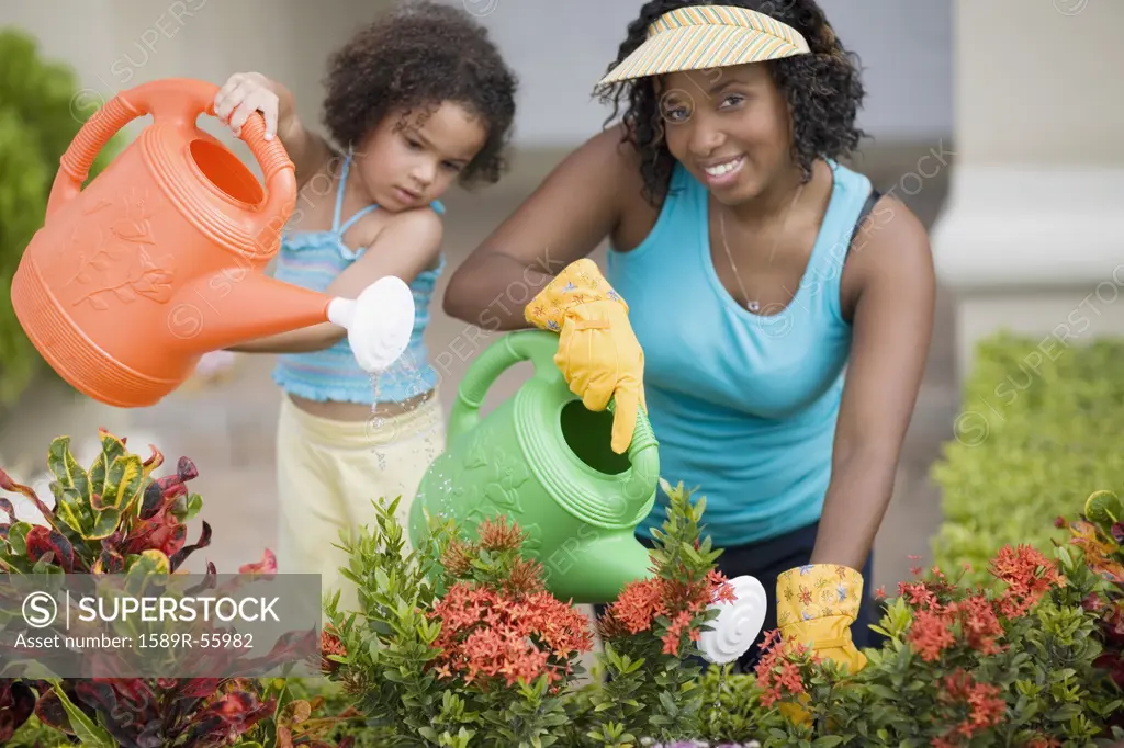 African mother and daughter watering flowers