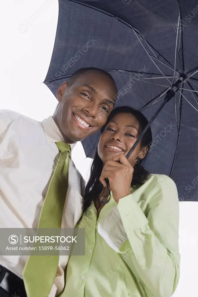 Hispanic couple standing under umbrella