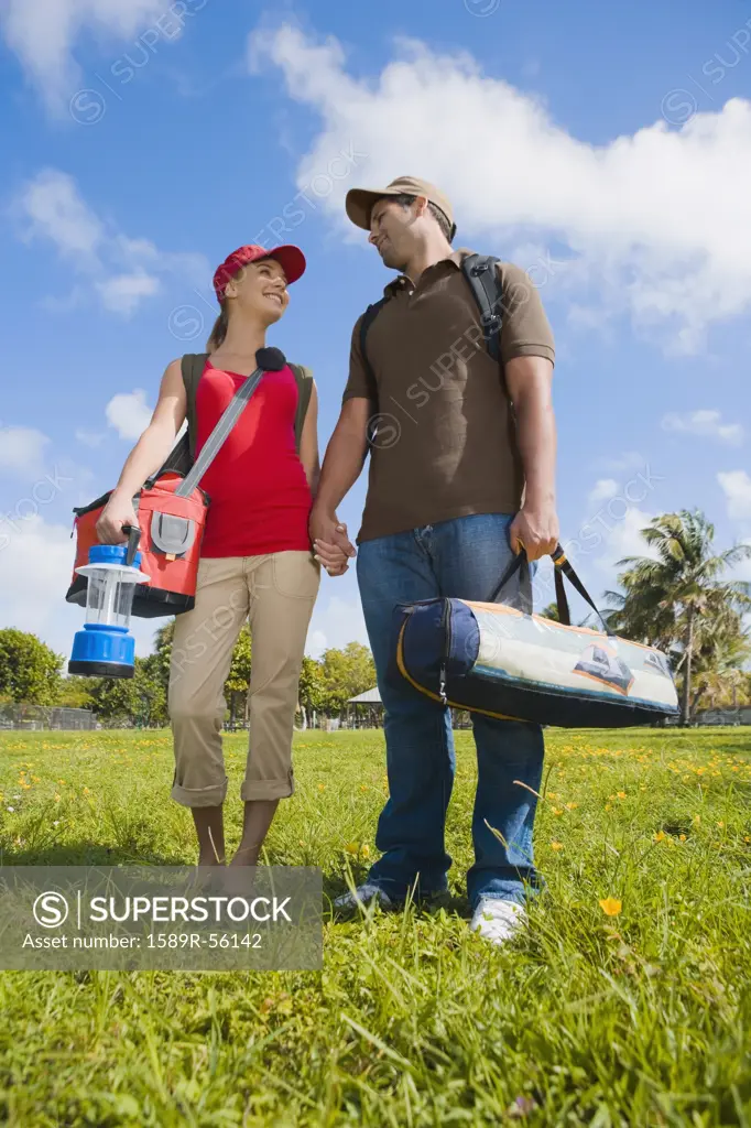 Hispanic couple carrying camping supplies