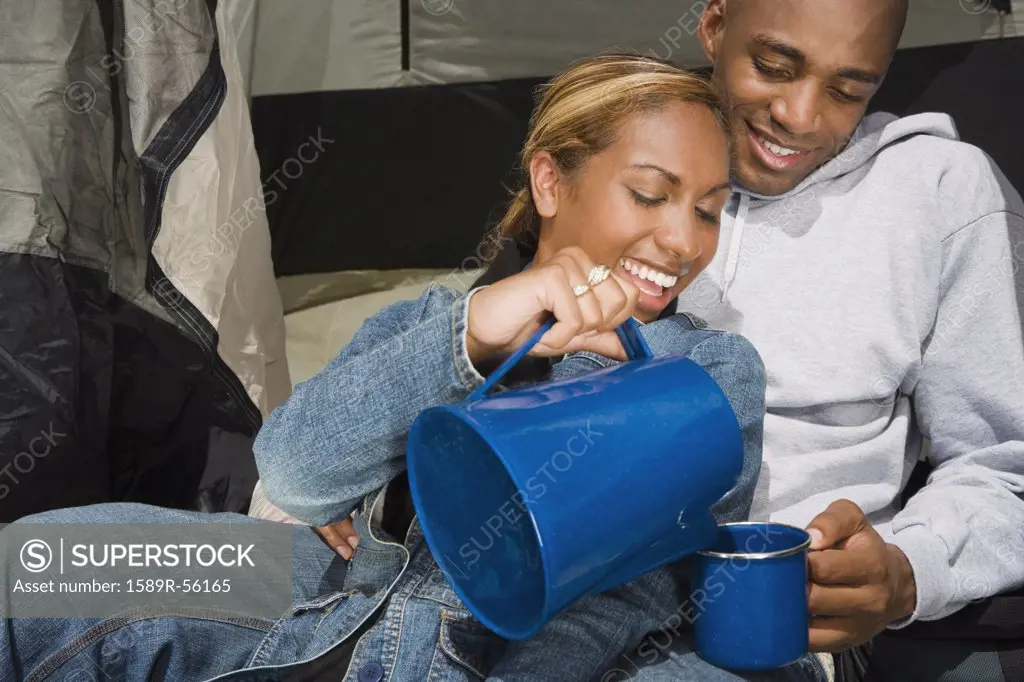 African couple drinking coffee at campsite