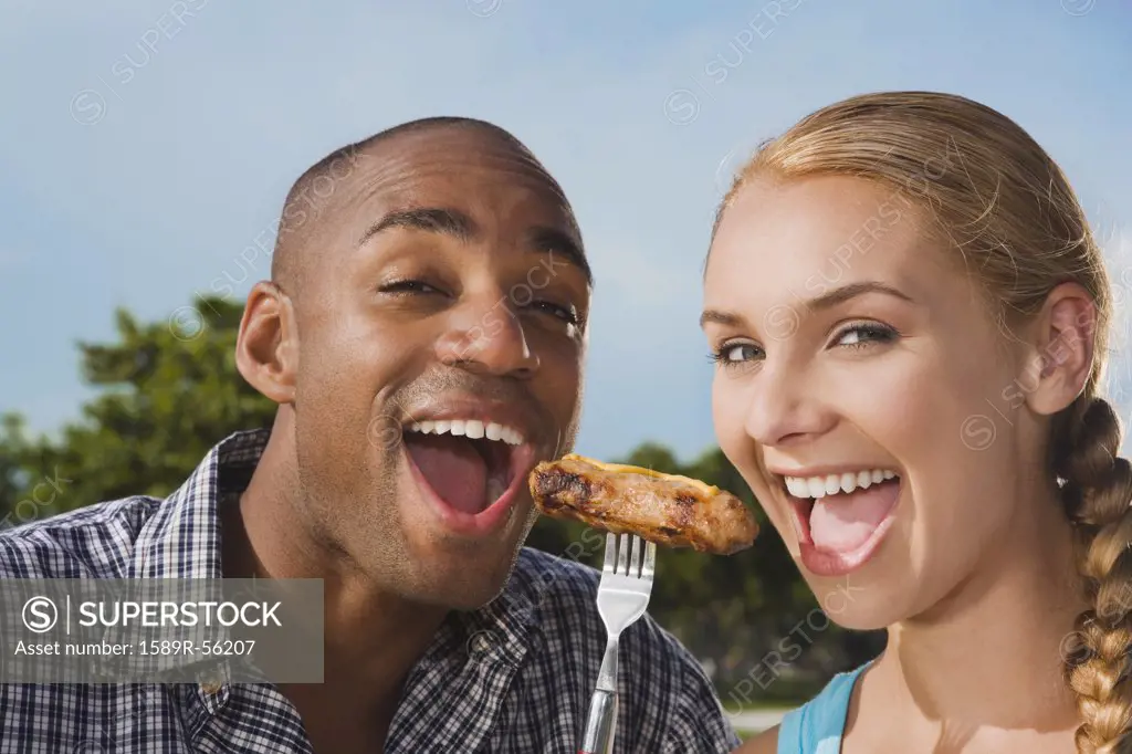 Multi-ethnic couple eating from same fork