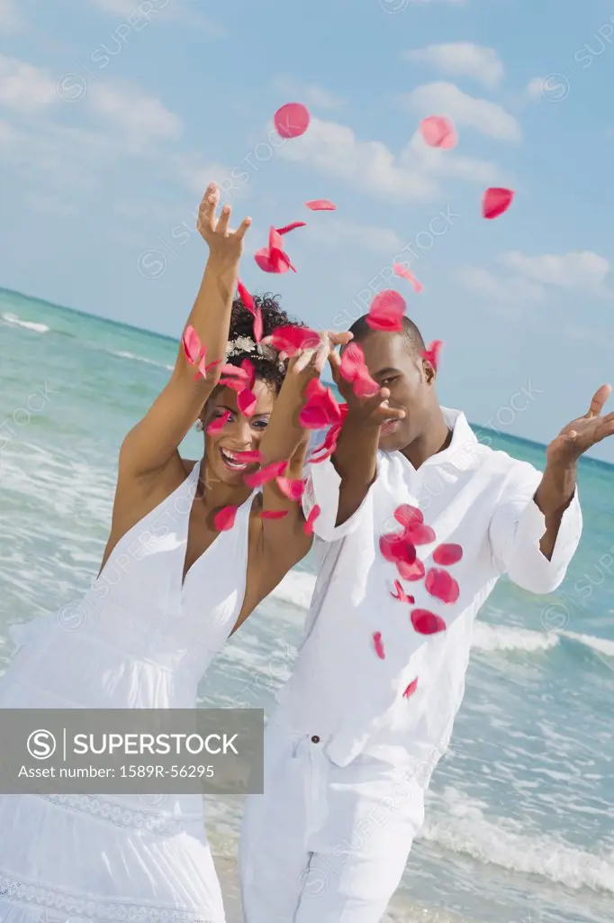 Multi-ethnic couple throwing flower petals in air