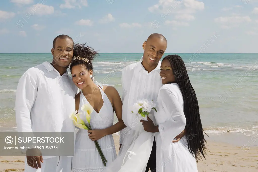 Multi-ethnic newlyweds hugging at beach