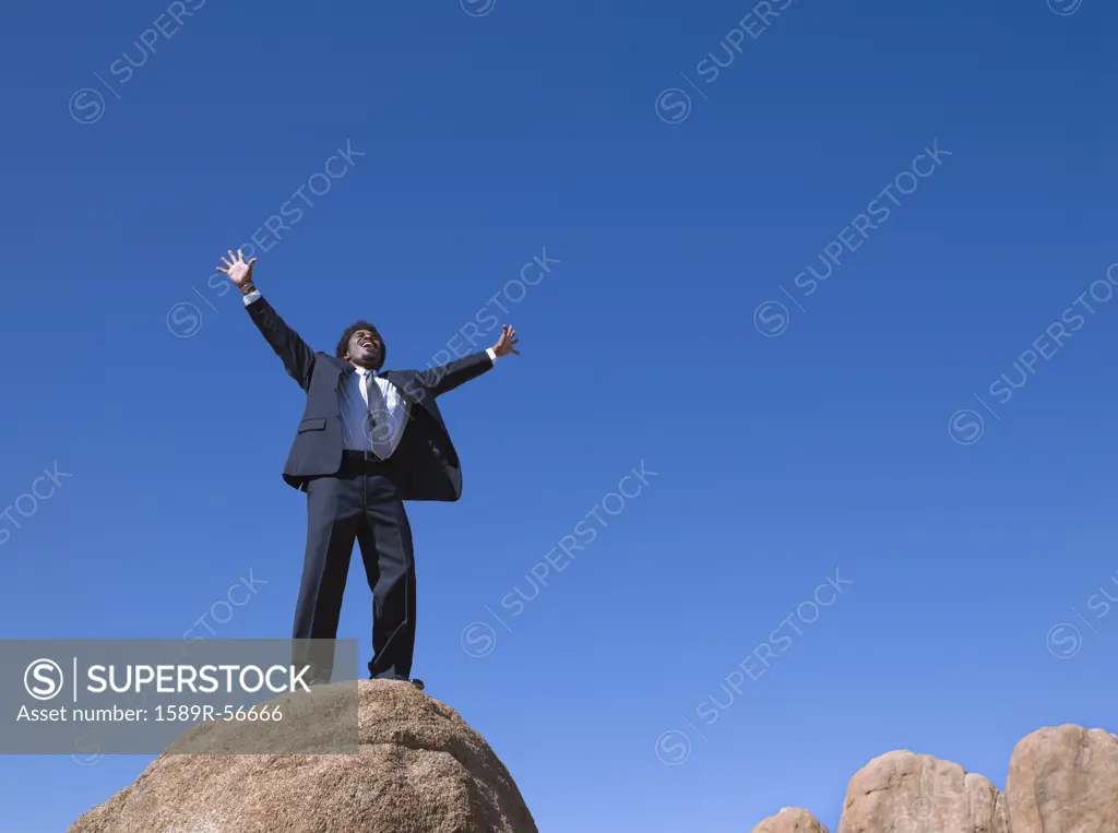 African businessman standing on top of rock