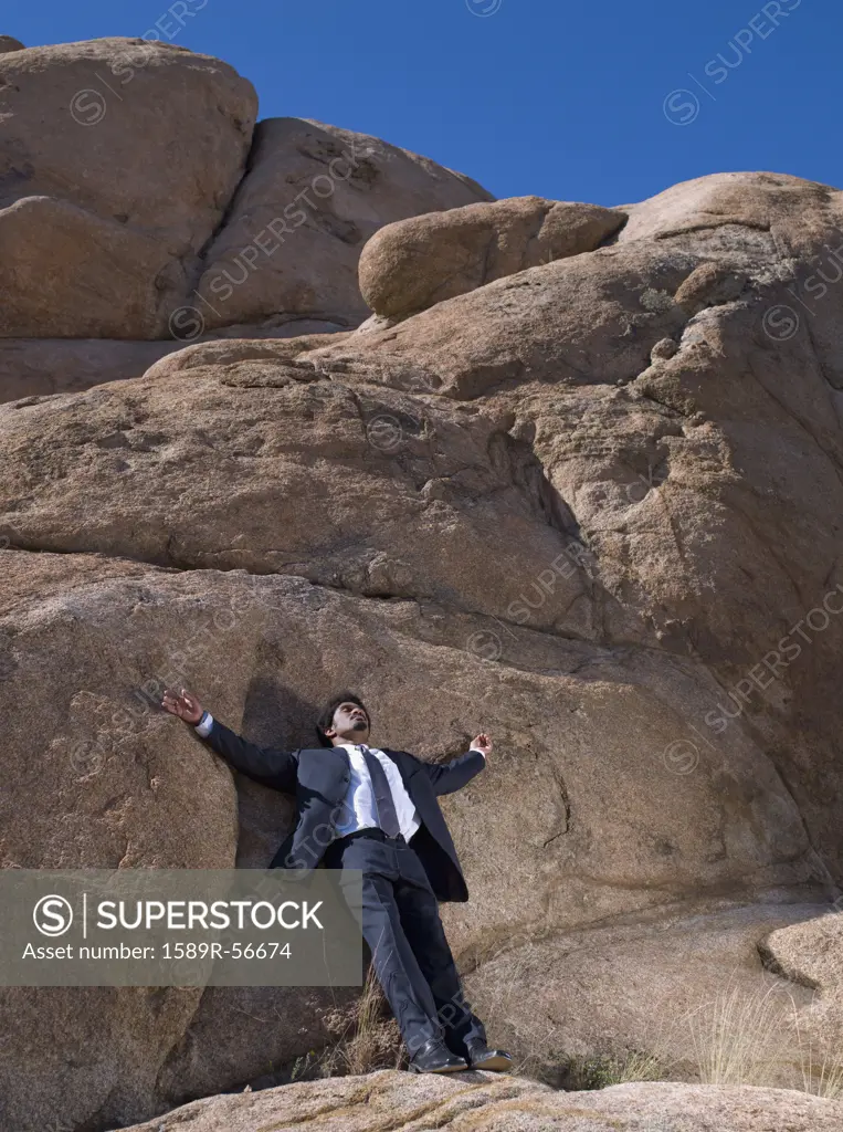 African businessman leaning on rock