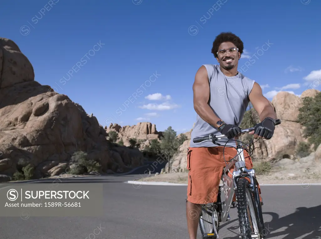 African man standing on mountain bike