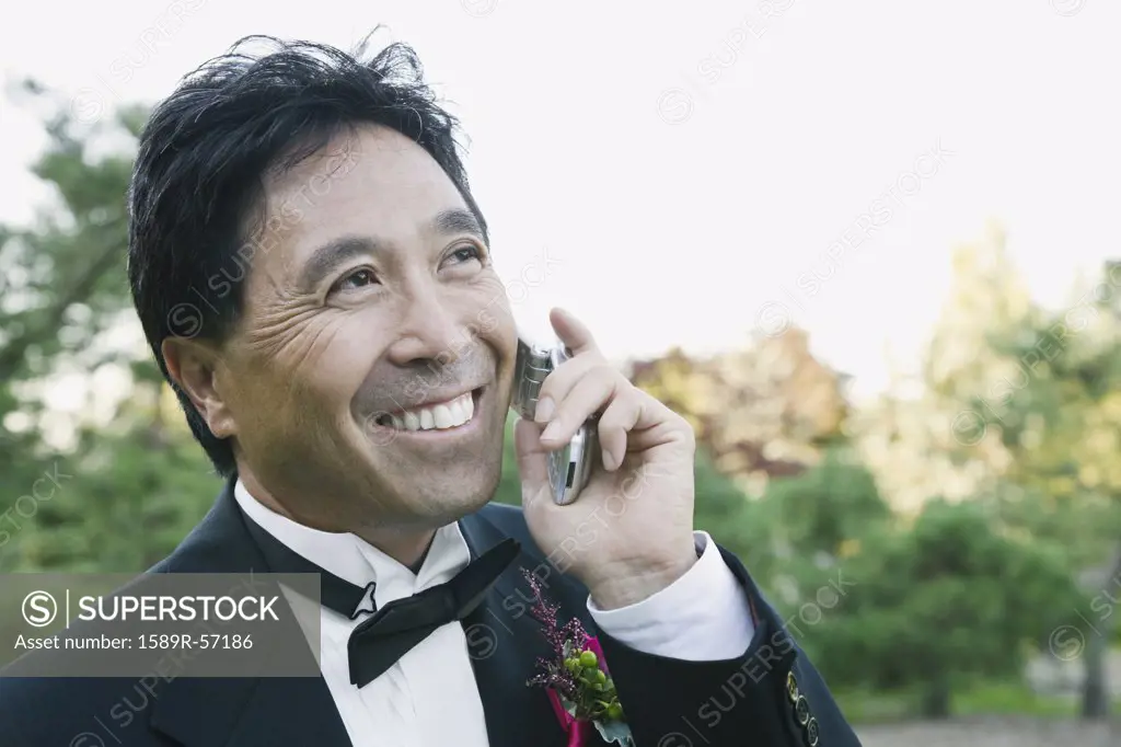 Asian groom talking on cell phone