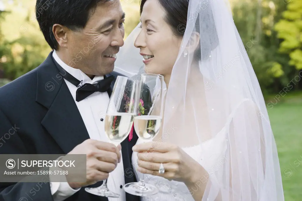 Asian newlyweds toasting with champagne