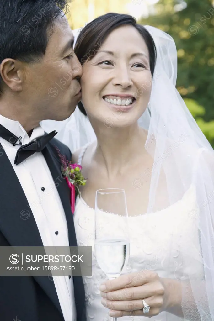 Asian groom kissing brides cheek