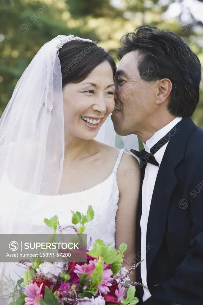 Asian groom telling secret to bride