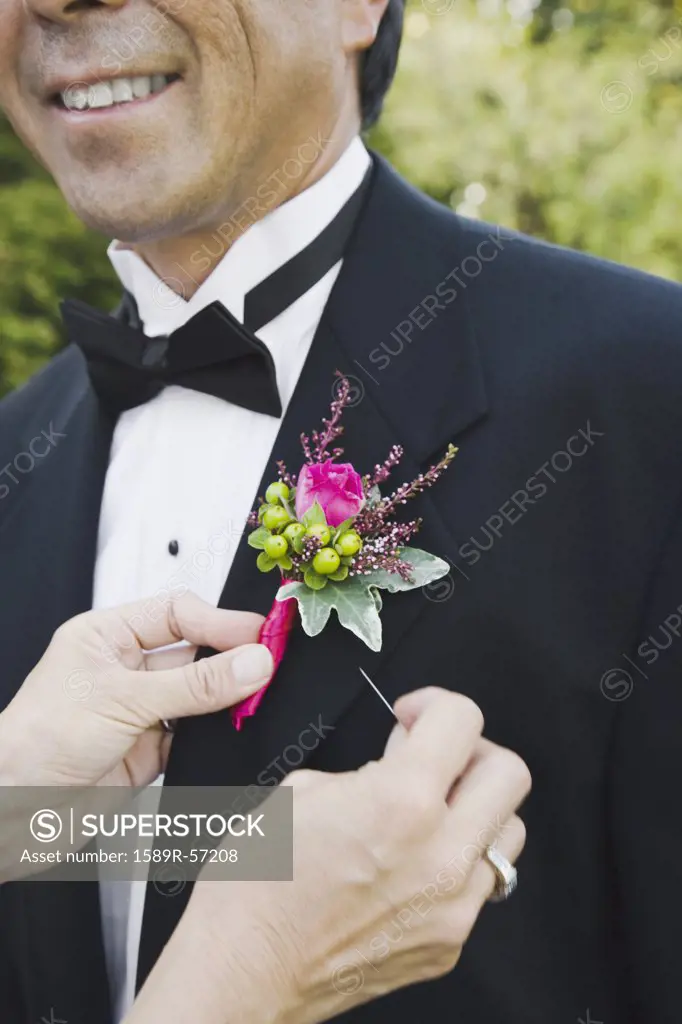 Asian woman pinning grooms boutonniere
