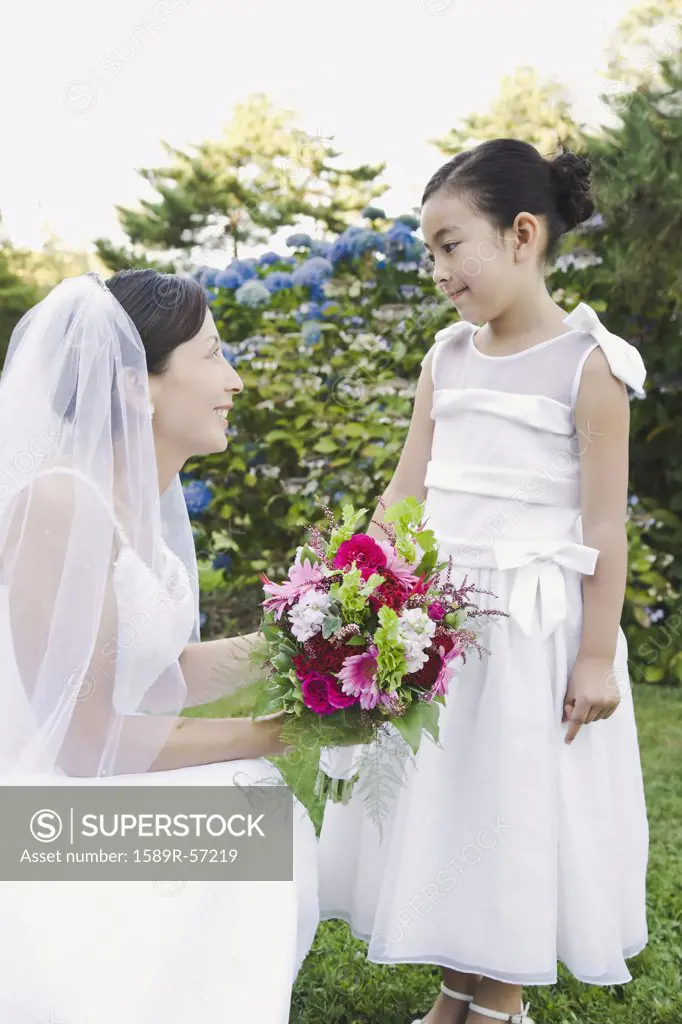 Asian bride smiling at flower girl