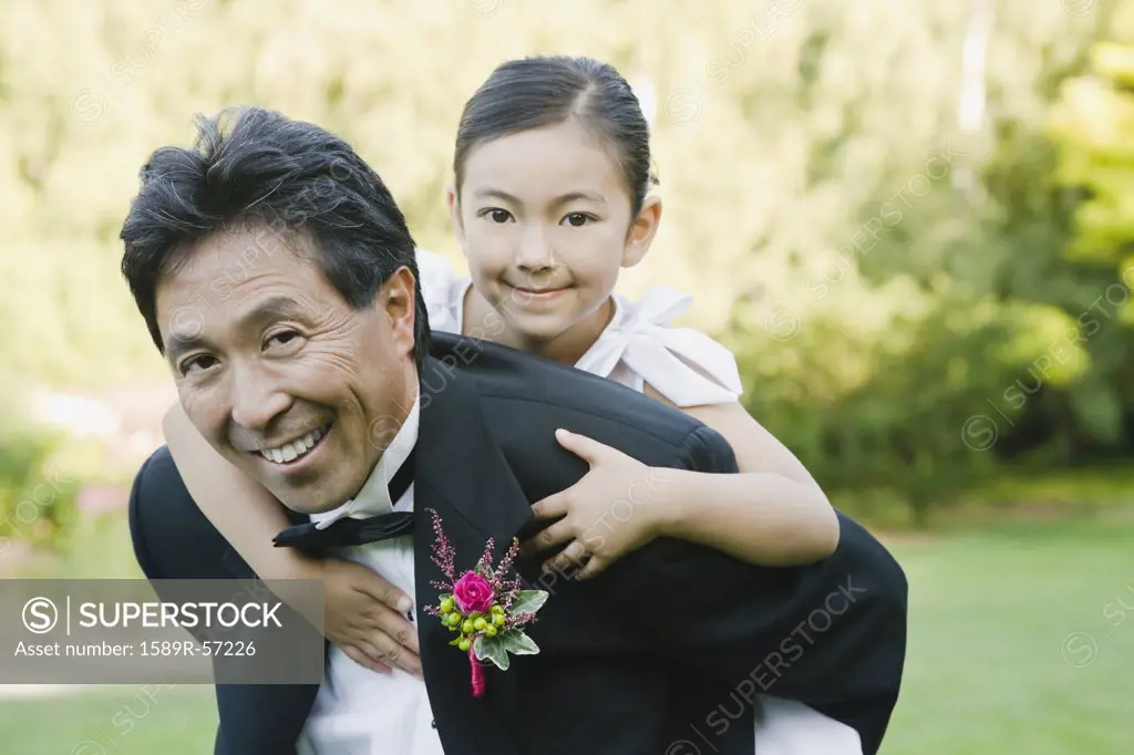 Asian father giving daughter piggy back ride
