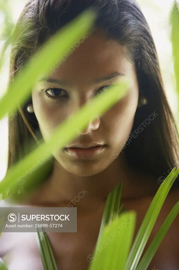 Hispanic woman looking through plant