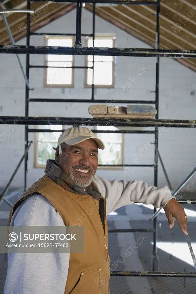 Hispanic man leaning on scaffolding