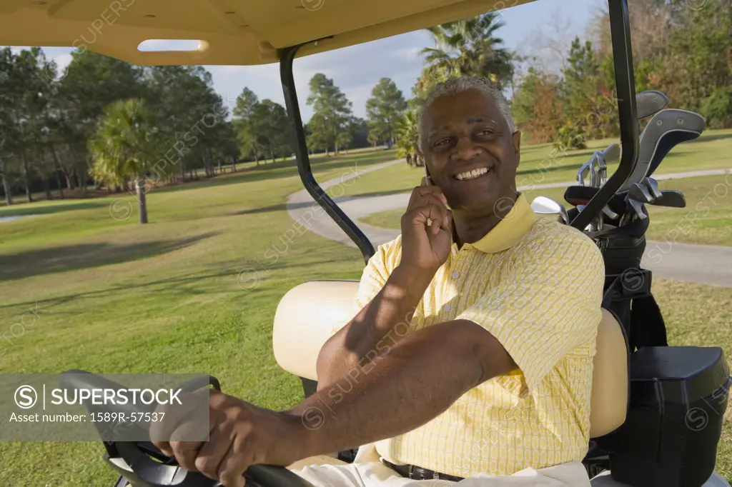 African man talking on cell phone in golf cart