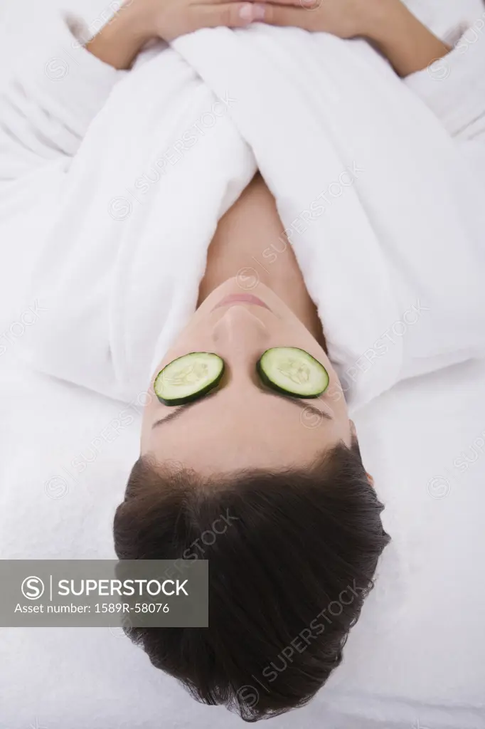 Hispanic woman with cucumber slices on eyes