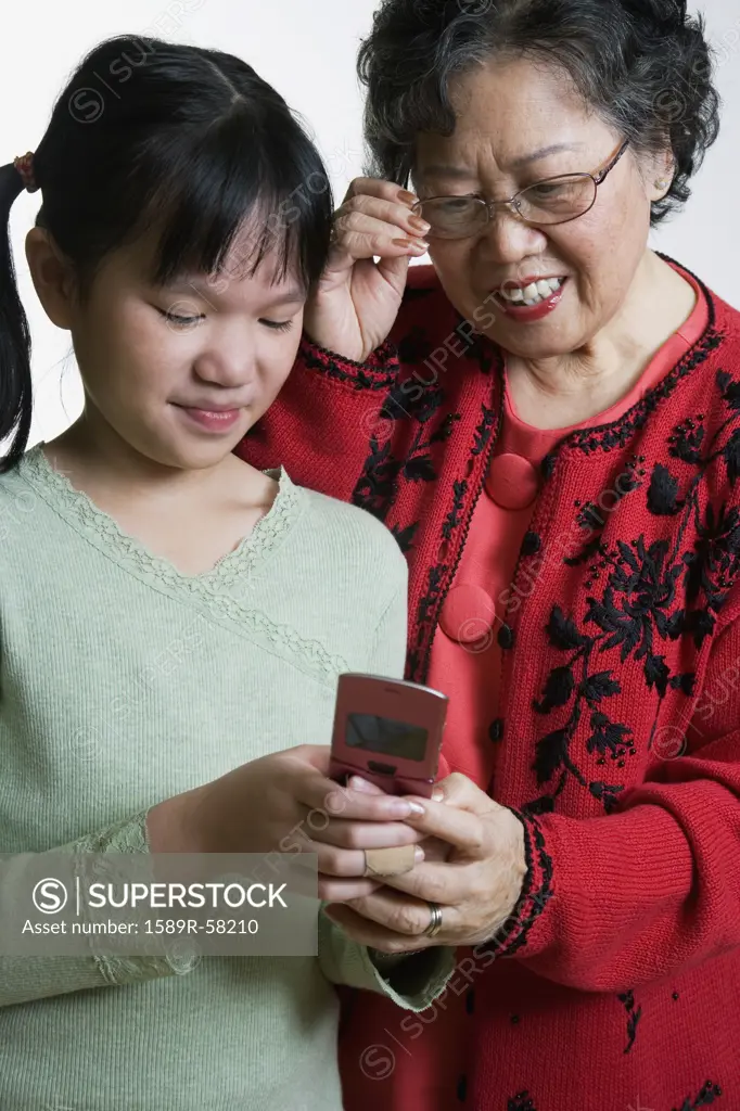 Asian grandmother and granddaughter looking at cell phone