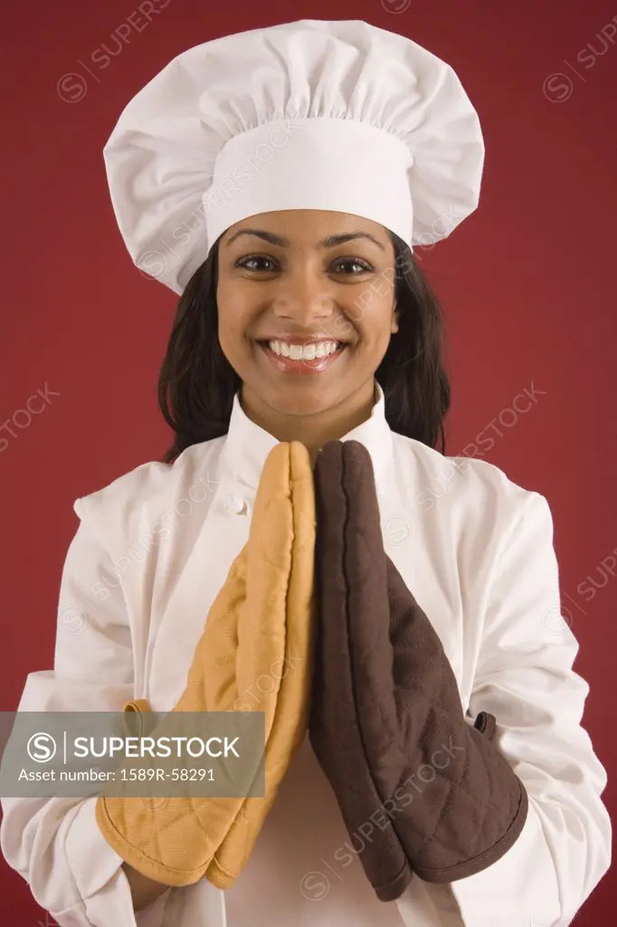 Indian female baker wearing oven mitts