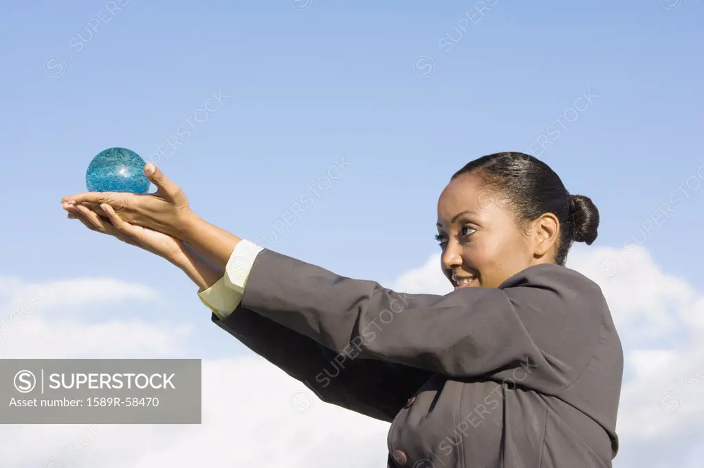 Hispanic businesswoman holding glass orb